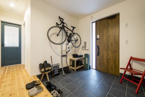趣味の自転車を壁掛け収納にした玄関。キャンプ用品などの手入れもできる広さ