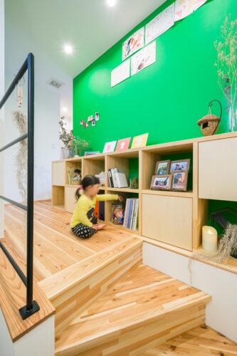 ２階に家族の本棚を配置。壁にグリーンを用いて遊び心をプラス。