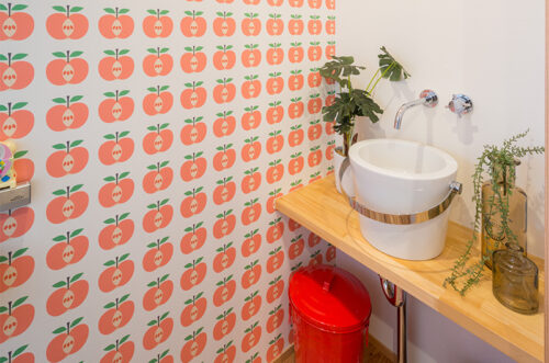 バケツ型のボウルとりんご柄の壁紙で楽しいトイレ空間に。